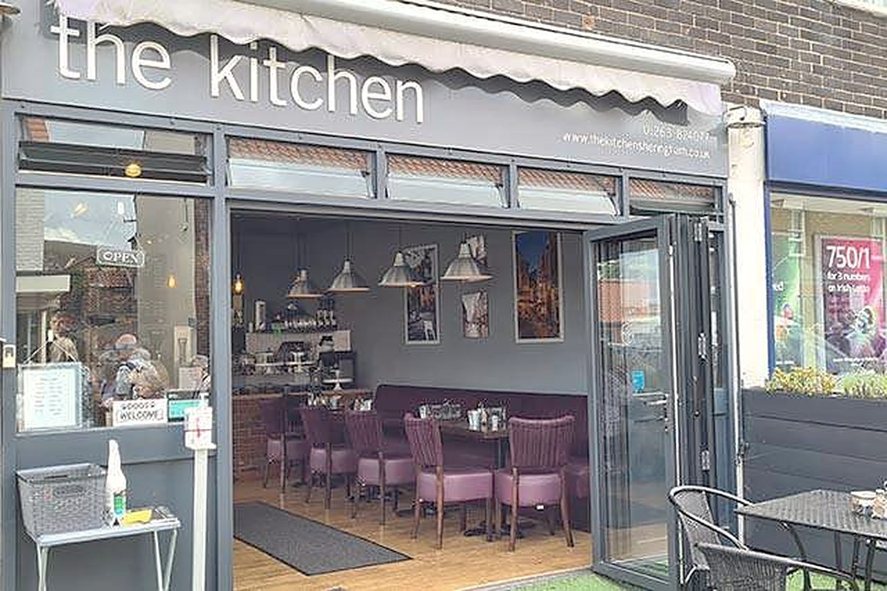 The Kitchen's shopfront: a grey awning reading 'the kitchen', folding glass doors and tables outside