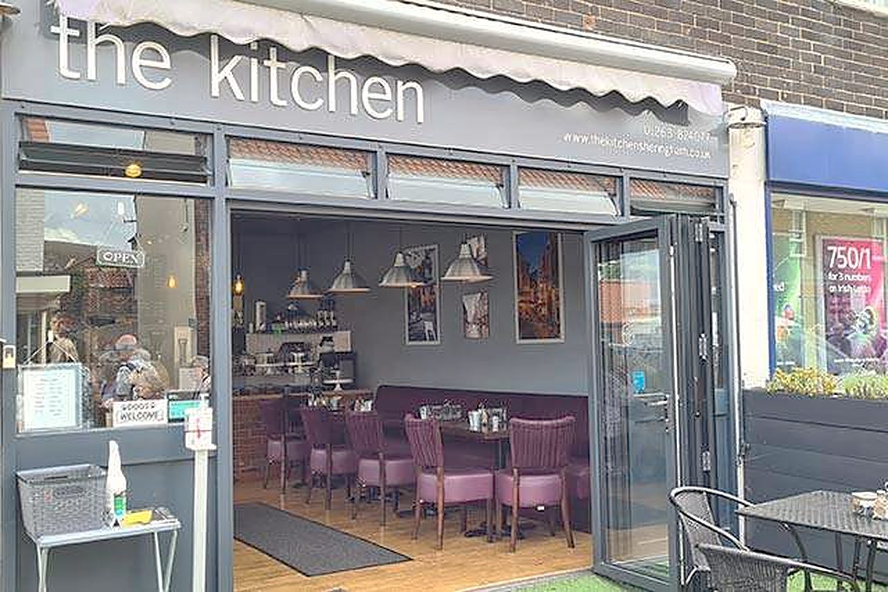 The Kitchen's shopfront: a grey awning reading 'the kitchen', folding glass doors and tables outside