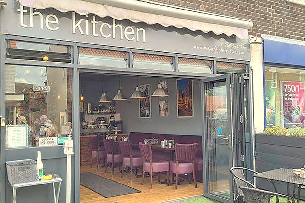 The Kitchen's shopfront: a grey awning reading 'the kitchen', folding glass doors and tables outside